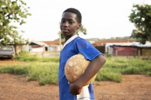side view smiley boy holding ball